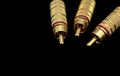 Three male metallic and gold rca type connectors in the foreground Royalty Free Stock Photo