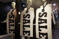 Three mannequins with large SALE signs around their necks