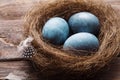 Three marble blue Easter eggs painted by hibiscus, in a nest on a wooden background close-up. The Symbol Of Easter Royalty Free Stock Photo