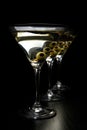 Three Martini drinks with olives on stick isolated on black table Royalty Free Stock Photo