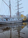 A three-masted sailboat in the bay, on the shore of which there is a picturesque yellow house