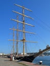 Three masted schooner with folded up sails moored at the pier in the port on a summer day Royalty Free Stock Photo