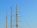 Three masts of a sailing ship with folded up sails and shrouds against a blue summer sky Royalty Free Stock Photo