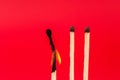 Igniting Spark: Burning Matchstick on Red Background Royalty Free Stock Photo