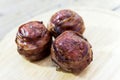 Three meatballs and covered with bacon on cutting board Royalty Free Stock Photo