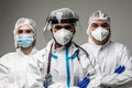 Three medical healthcare workers in biohazard protective tools standing isolated on gray background. Ready to fight with covid19 Royalty Free Stock Photo