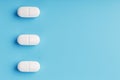 Three medicinal tablets in a row on a blue background, isolate Royalty Free Stock Photo