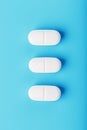 Three medicinal tablets in a row on a blue background, isolate Royalty Free Stock Photo