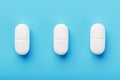 Three medicinal tablets in a row on a blue blue background, isolate Royalty Free Stock Photo