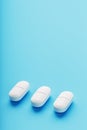 Three medicinal tablets in a row on a blue blue background, isolate Royalty Free Stock Photo