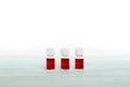 Three medicine vials filled with red liquid