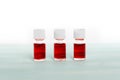 Three medicine vials filled with red liquid close up