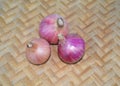 Three medium sized red colored fresh onion gathered together on a wood background Royalty Free Stock Photo