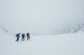 Three members rope team ascending the high mountain winter peak. Blizard covering the structural basin in Vysoke Tatry (High Royalty Free Stock Photo