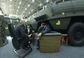 Three men businessmen sitting in the lounge zone in front of armored personnel carrier and negotiating