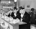 Three men with hats eating at the counter of a diner Royalty Free Stock Photo
