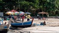 Three men prepping a fishing boat at the beach on the Bay of Bengal in Ngwesaung City, Myanmar