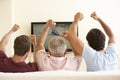 Three Men Watching Widescreen TV At Home