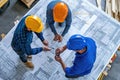 Three men, wearing hard hats and holding blueprints, collaborate on a construction project, Architects and engineers collaborating Royalty Free Stock Photo