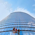 Three men workers in red and dark work clothes cleaning the exterior windows, bottom view. Outdoor