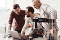 Three men are working on preparing a 3d printer for printing. One of them explains the rest of the subtlety the print. Royalty Free Stock Photo