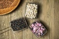 Three metal baskets with colorful beans on a rough wooden table