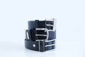 Three metal buckles male leather black belt stacked in a pile on white background close-up Royalty Free Stock Photo