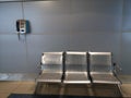 Three metal chairs and landline in metro station train waiting room