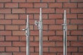 Three metal light stands with fastening mechanism above a red brick wall background