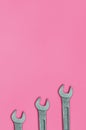 Three metallic spanners lie on texture background of fashion pastel pink color paper in minimal concept