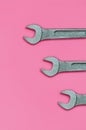 Three metallic spanners lie on texture background of fashion pastel pink color paper in minimal concept