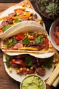 Three Mexican tacos with marbled beef, black Angus and vegetables on old rustic table. Mexican dish with sauces guacamole and sals Royalty Free Stock Photo