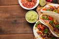 Three Mexican tacos with marbled beef, black Angus and vegetables on old rustic table. Mexican dish with sauces guacamole and sals Royalty Free Stock Photo