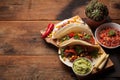 Three Mexican tacos with marbled beef, black Angus and vegetables on old rustic table. Mexican dish with sauces guacamole and sals Royalty Free Stock Photo