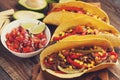 Three Mexican tacos with minced beef and mix vegetables on old rustic table. Mexican dish with sauces salsa in bowl and avocado. S Royalty Free Stock Photo