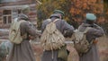 Three military men with big bags on their back are aiming.