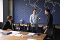Three millennial businessmen negotiating during briefing in modern boardroom