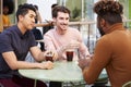 Three millennial male friends talking over cold brews outside a cafe in a city street, close up Royalty Free Stock Photo