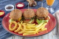 Three different burger with pickles onion rings and french fries on red plate with copy space, top view Royalty Free Stock Photo