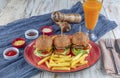 Three different burger with pickles onion rings and french fries on red plate with copy space, top view Royalty Free Stock Photo