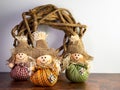 Three Mini Stuffed Scarecrows with Plaid Clothes and a Burlap Hat with a Wooden Wreath, perfect for Halloween and Fall or Royalty Free Stock Photo