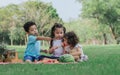 Three mixed race caucasian little cute children kids sitting, playing in outdoor green park for picnic, eating fruit, watermelon Royalty Free Stock Photo