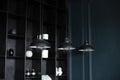 Three modern black ceiling lamps hang in room, close-up. Loft room interior. Metal chandeliers in retro style on background wooden Royalty Free Stock Photo