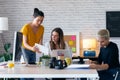 Three modern businesswomen talking and reviewing the latest work done on the digital tablet in a joint workspace