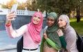 Three Modern Islamic Ladies Making Selfie On Phone In Park