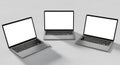 Three modern silver laptops with blank screens arranged in a triangle formation on a light surface Royalty Free Stock Photo