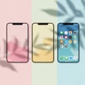 Three modern smartphones displayed side by side showcasing different wallpaper designs and app interfaces on a pastel background Royalty Free Stock Photo
