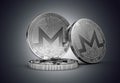 Three Monero cryptocurrency physical concept coin on gently lit dark background.