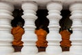 Three monks in orange robes behind four pillars