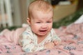 Three month old girl crying, lies on his stomach and is very upset, sad emotions in  child Royalty Free Stock Photo